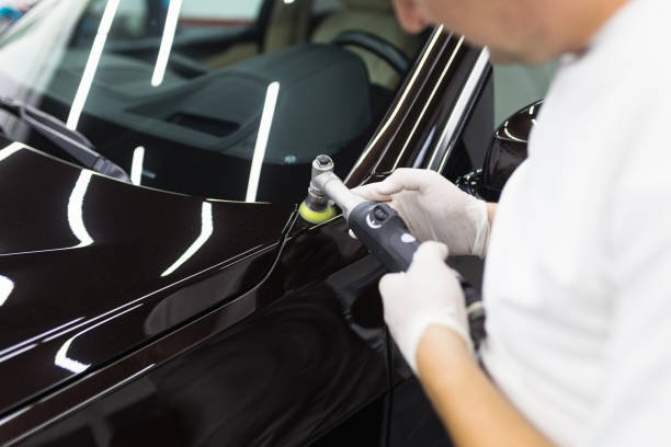 Car detailing - Worker with orbital polisher in auto repair shop.